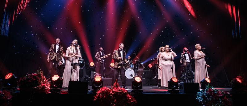 El grupo en directo sobre el escenario con la banda, bajo focos rojos y azules